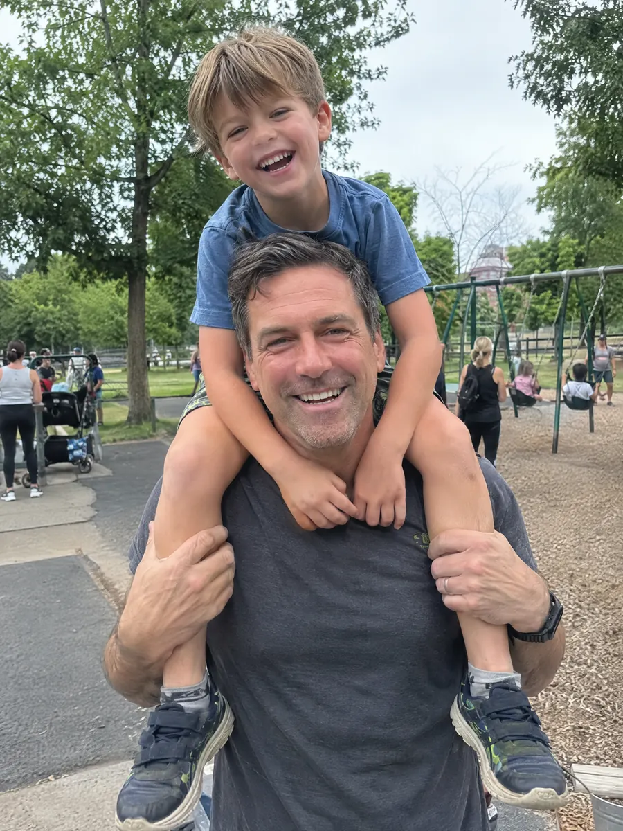 A father with his son on his shoulders at the playground